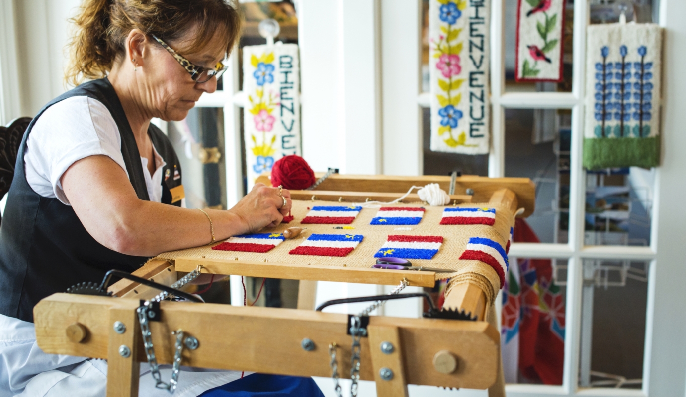 woman crafts small Acadian flags