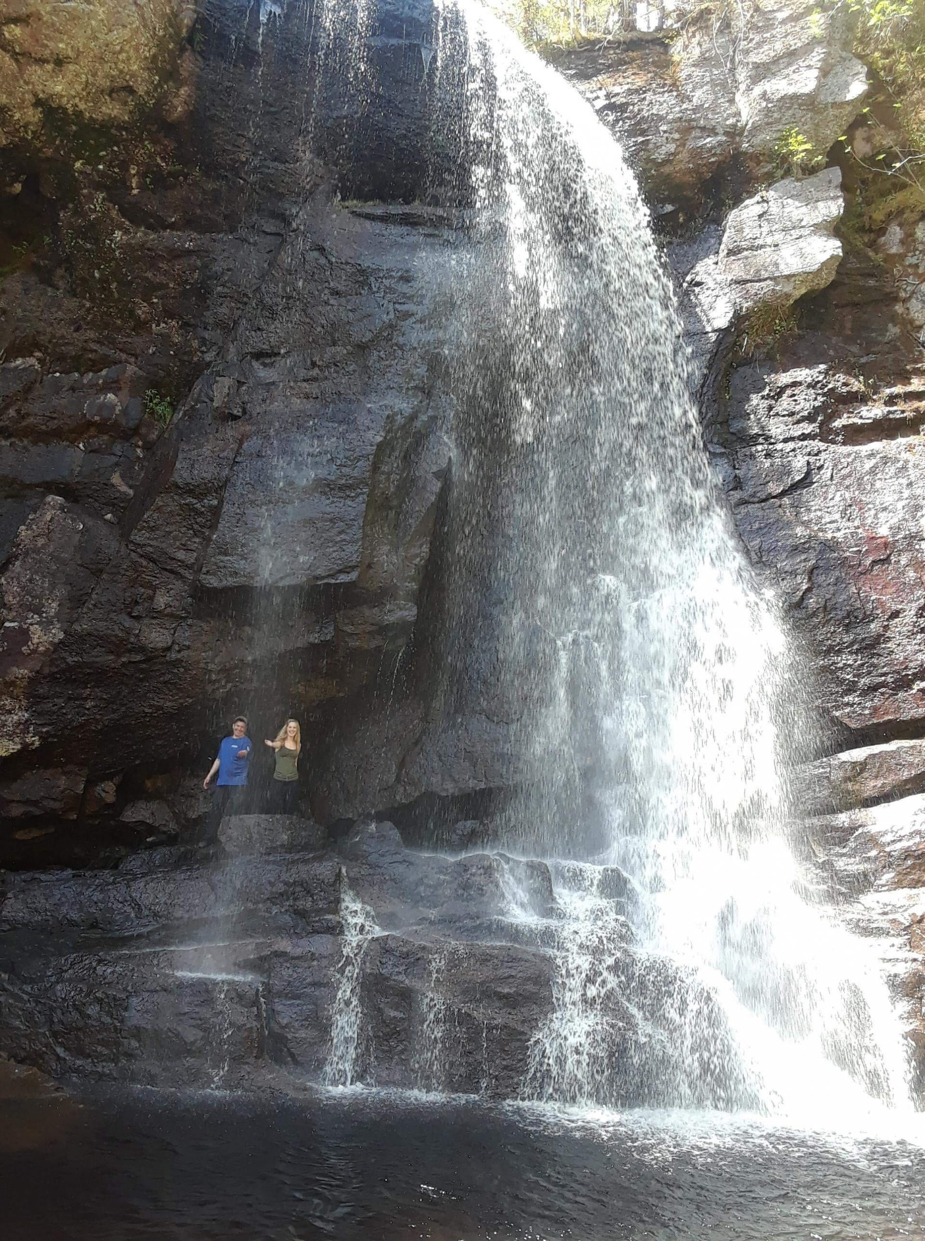 Hikers stand next to a large waterfall