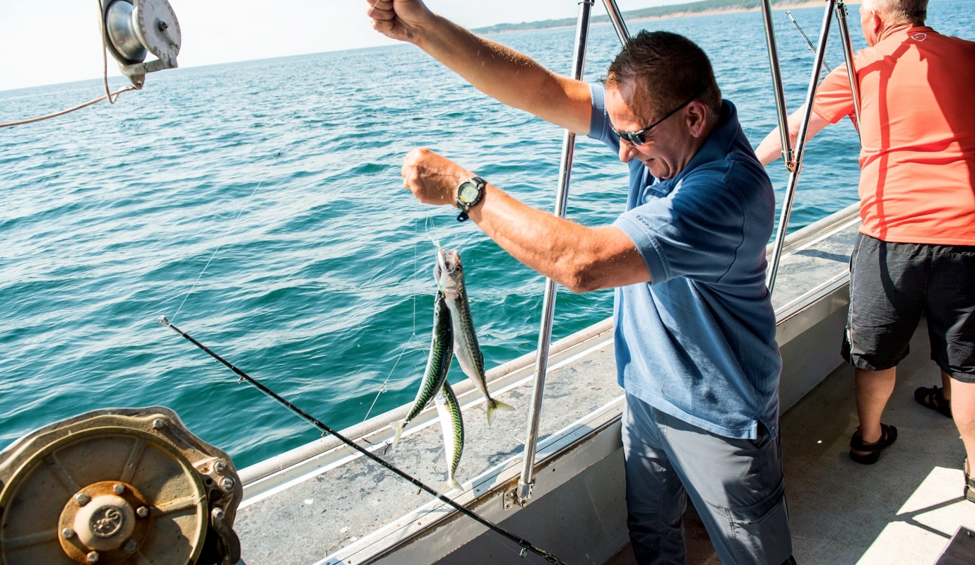 A man holds up the fish he's caught