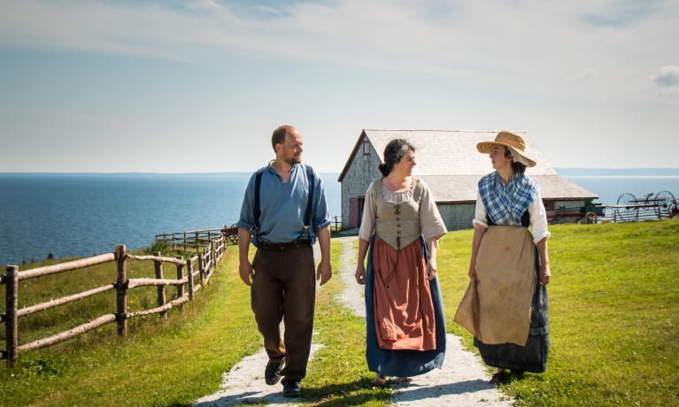 three Cape Bretoners in historic clothing walk outside