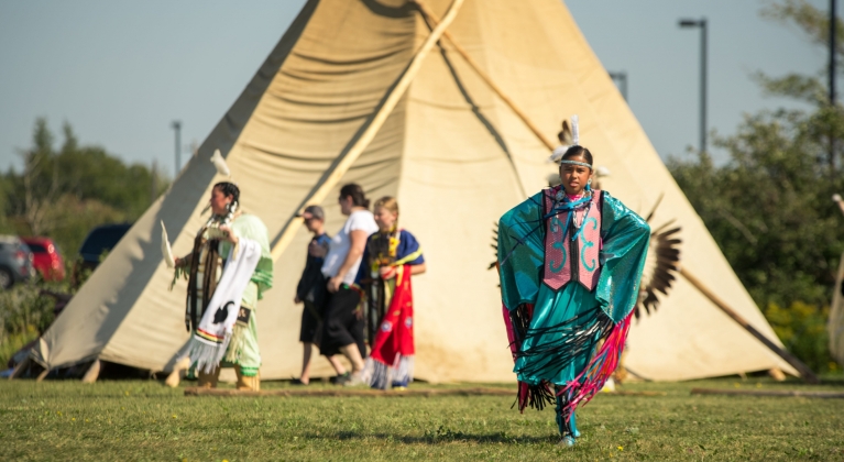 People dressed in traditional robes in front of a large tent
